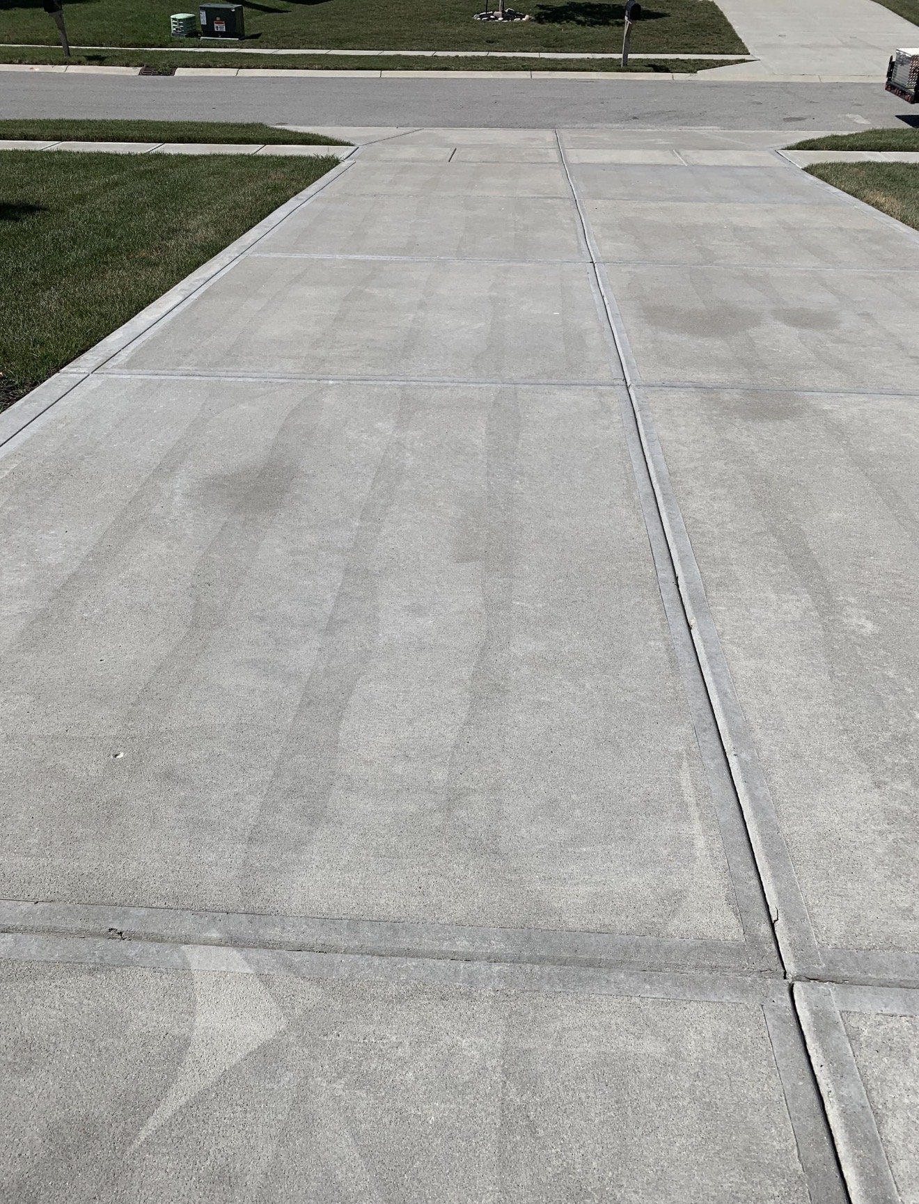 Tiger stripe wand marks permanently etched into a concrete driveway by improper pressure washing