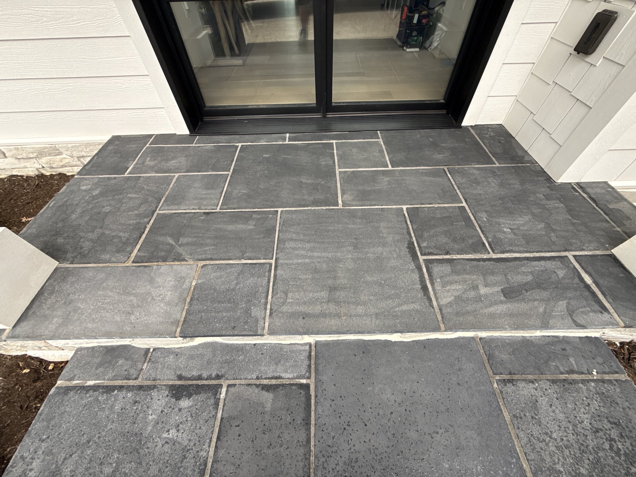 Pale etch marks left on a bluestone patio by high pressure washing