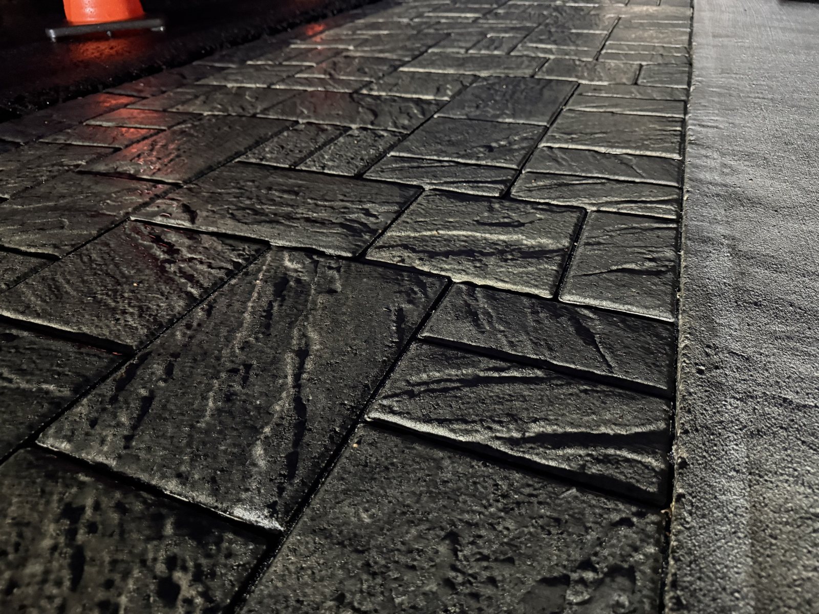 Freshly sealed pavers at night reflecting the light from a traffic cone, showing the gloss of the sealer film