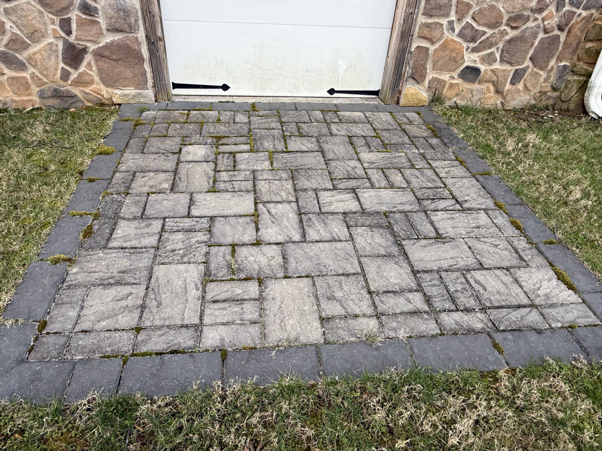Mossy paver patio by the garage before restoration in Huddleston, VA