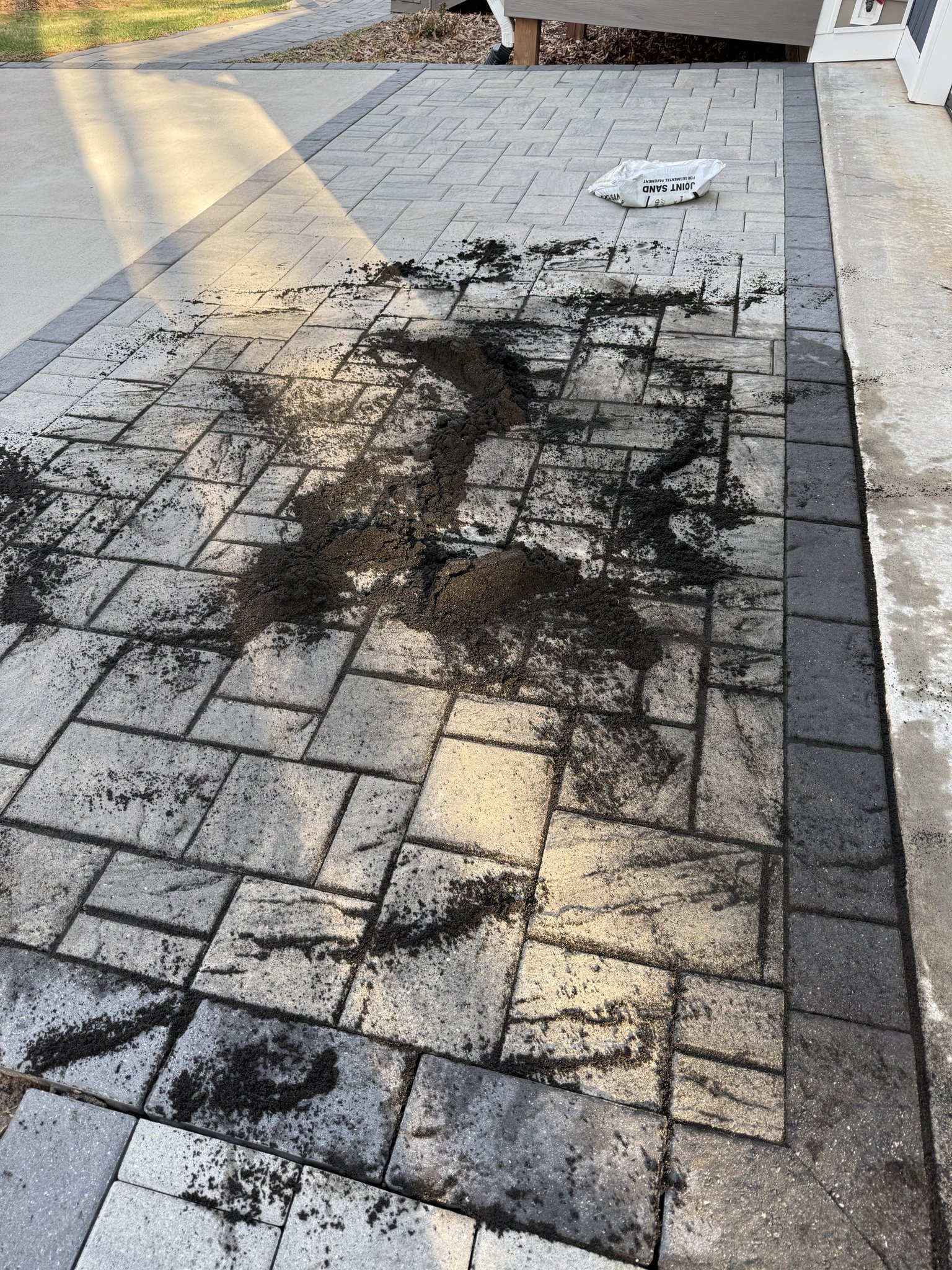 Joint sand being installed across the paver walkway