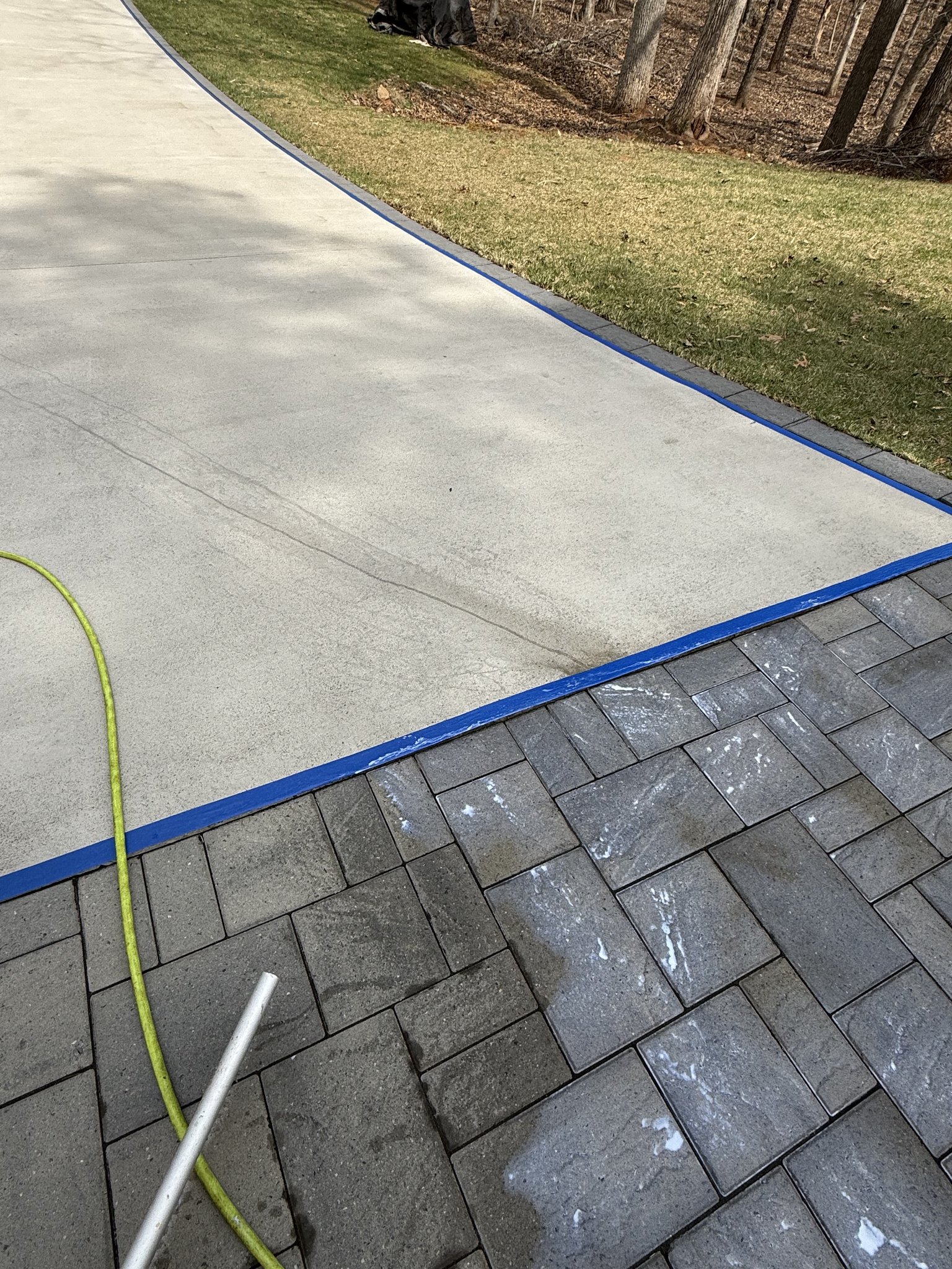 Taped concrete edges protecting the driveway during paver sealer application