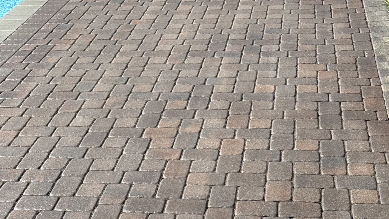 Finished paver pool deck after cleaning and sealing in Rocky Mount, VA — deep brown and charcoal color restored