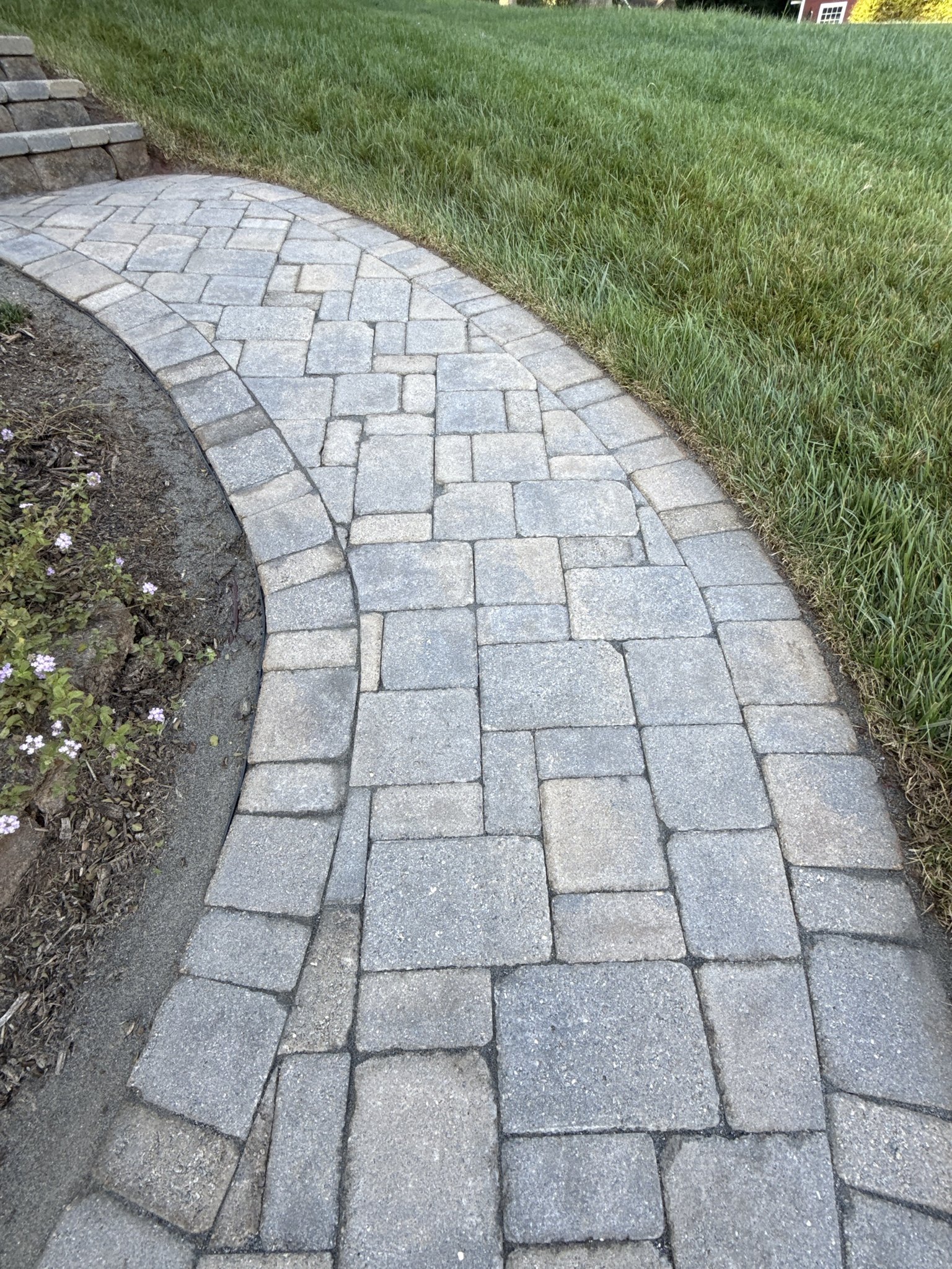 Clean paver walkway curving alongside the retaining wall after restoration in Huddleston, VA