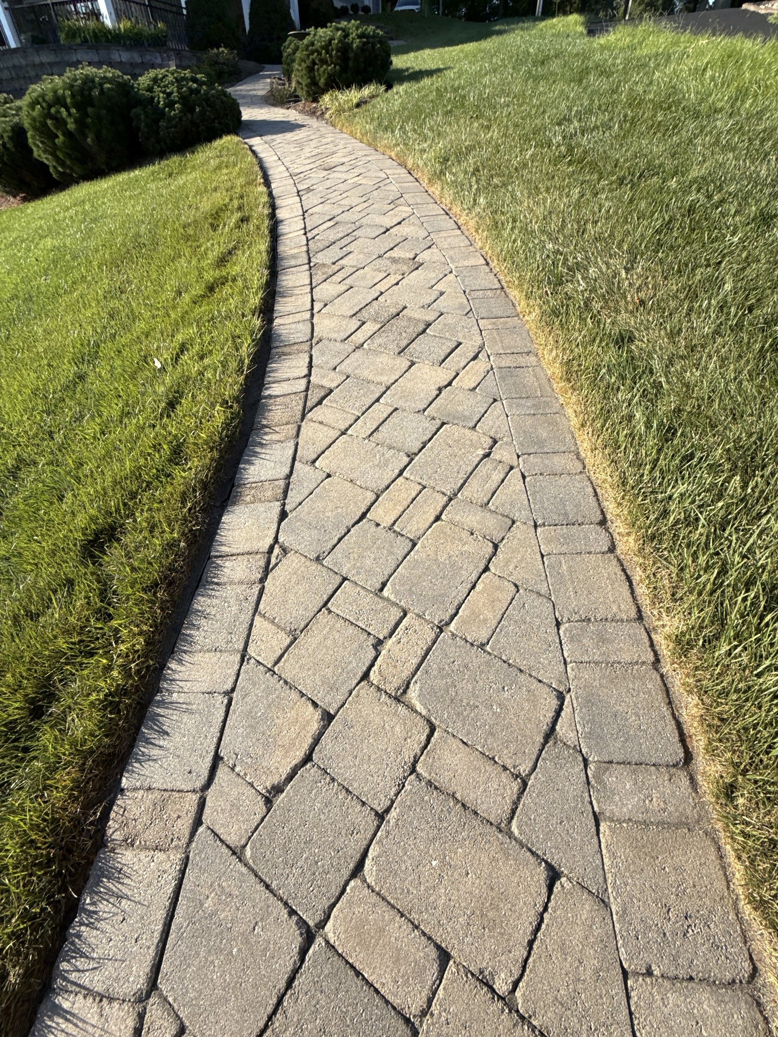 Restored paver walkway curving through the lawn after sealing in Huddleston, VA