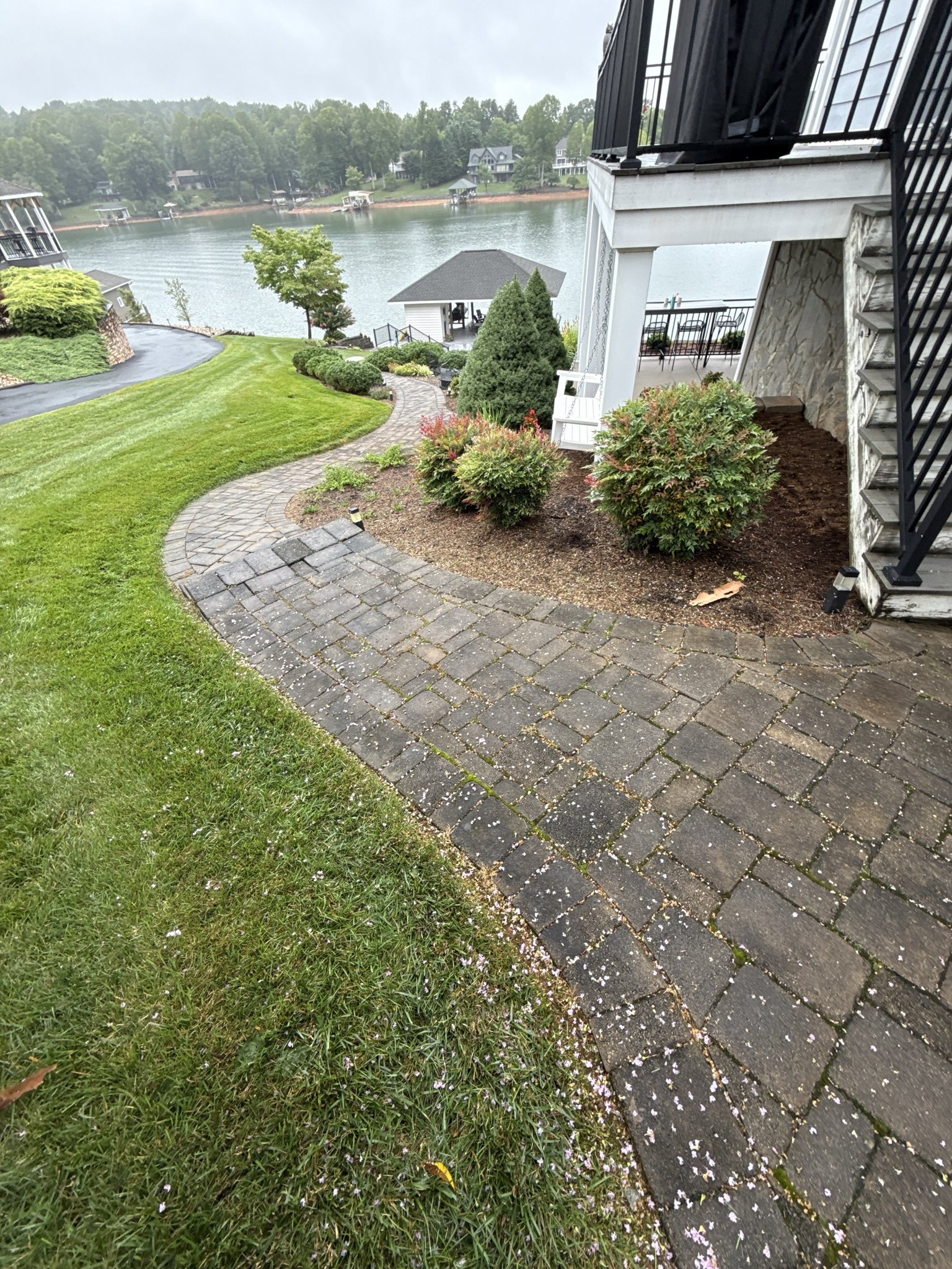 Darkened paver walkway with moss in the joints running past the deck stairs in Huddleston, VA