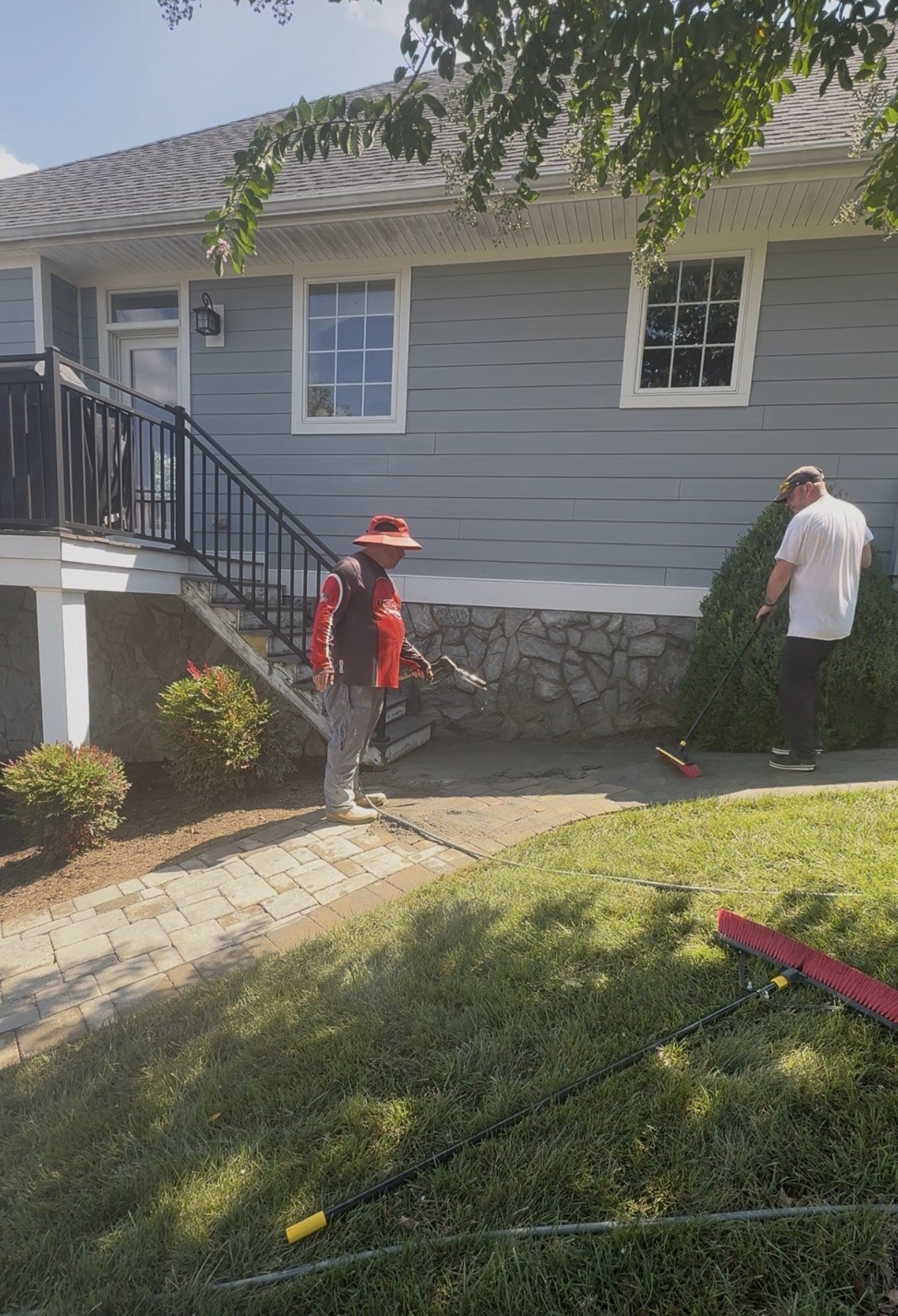 Working new fieldstone joint sand into the paver walkway beside the house in Huddleston, VA