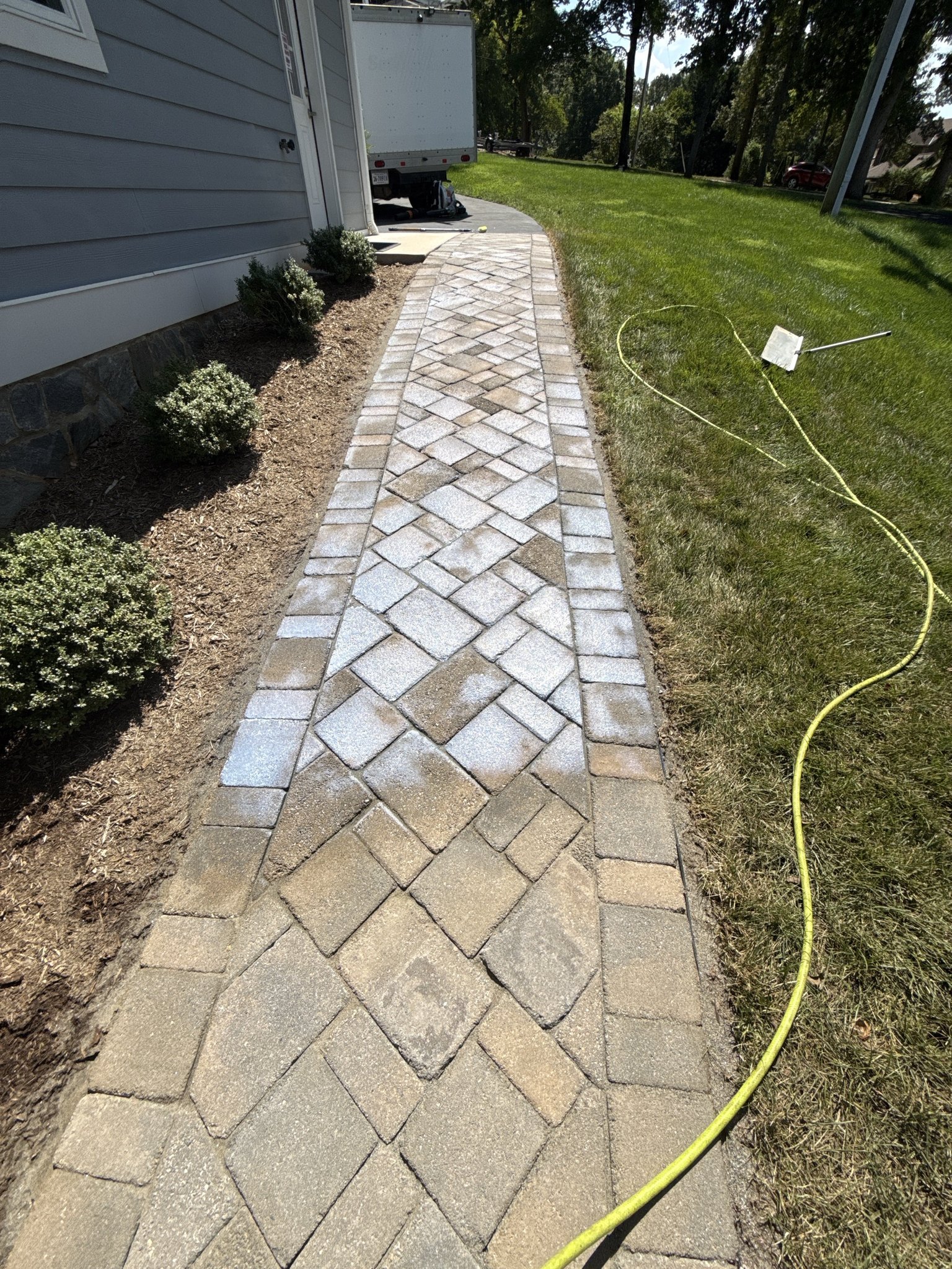 Water-based acrylic sealer going down milky across the pavers before it dries clear