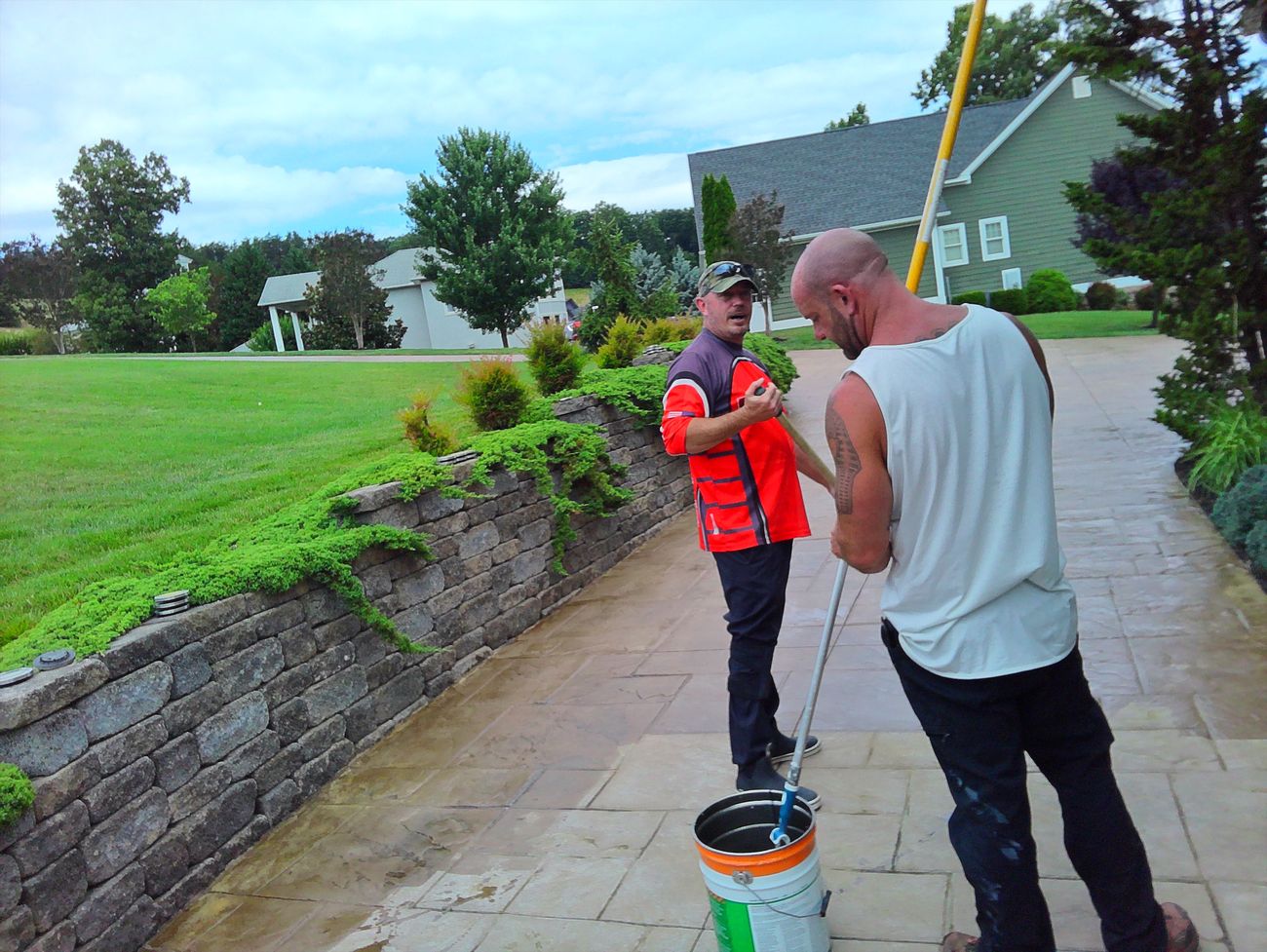 Two-man Pro-Shine crew applying concrete sealer from bucket