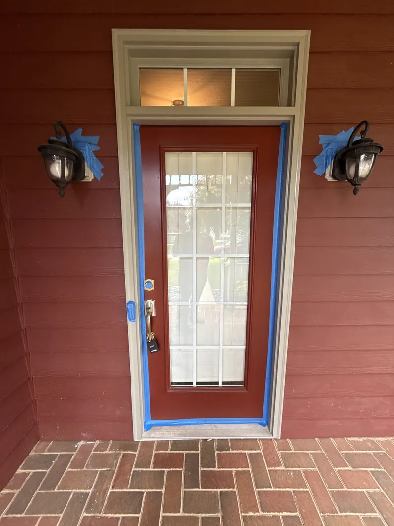 Front door and light fixtures masked before soft washing a home in Vinton, VA